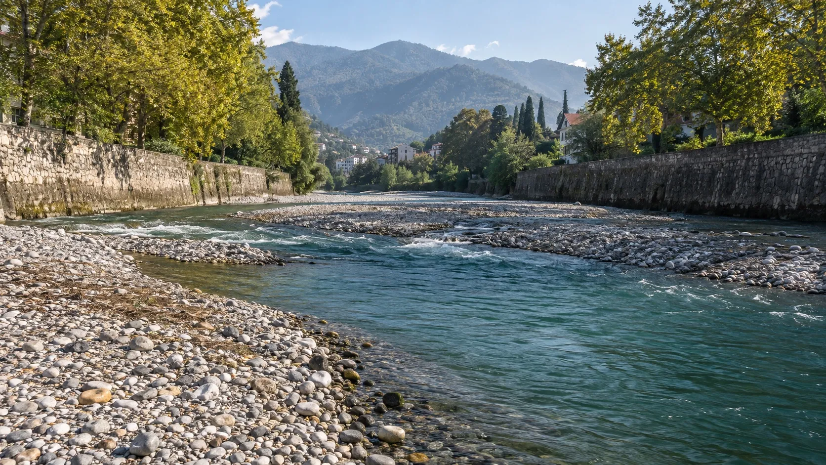 Галечное русло горной реки между каменными набережными