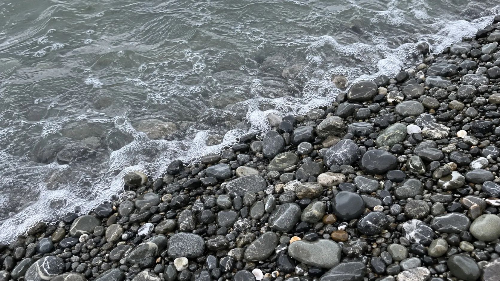 Мокрая галька и пена у кромки воды (сгенерированная иллюстрация)
