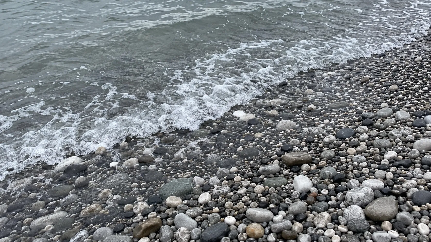 Галька у кромки воды. Иллюстрация, не конкретный пляж