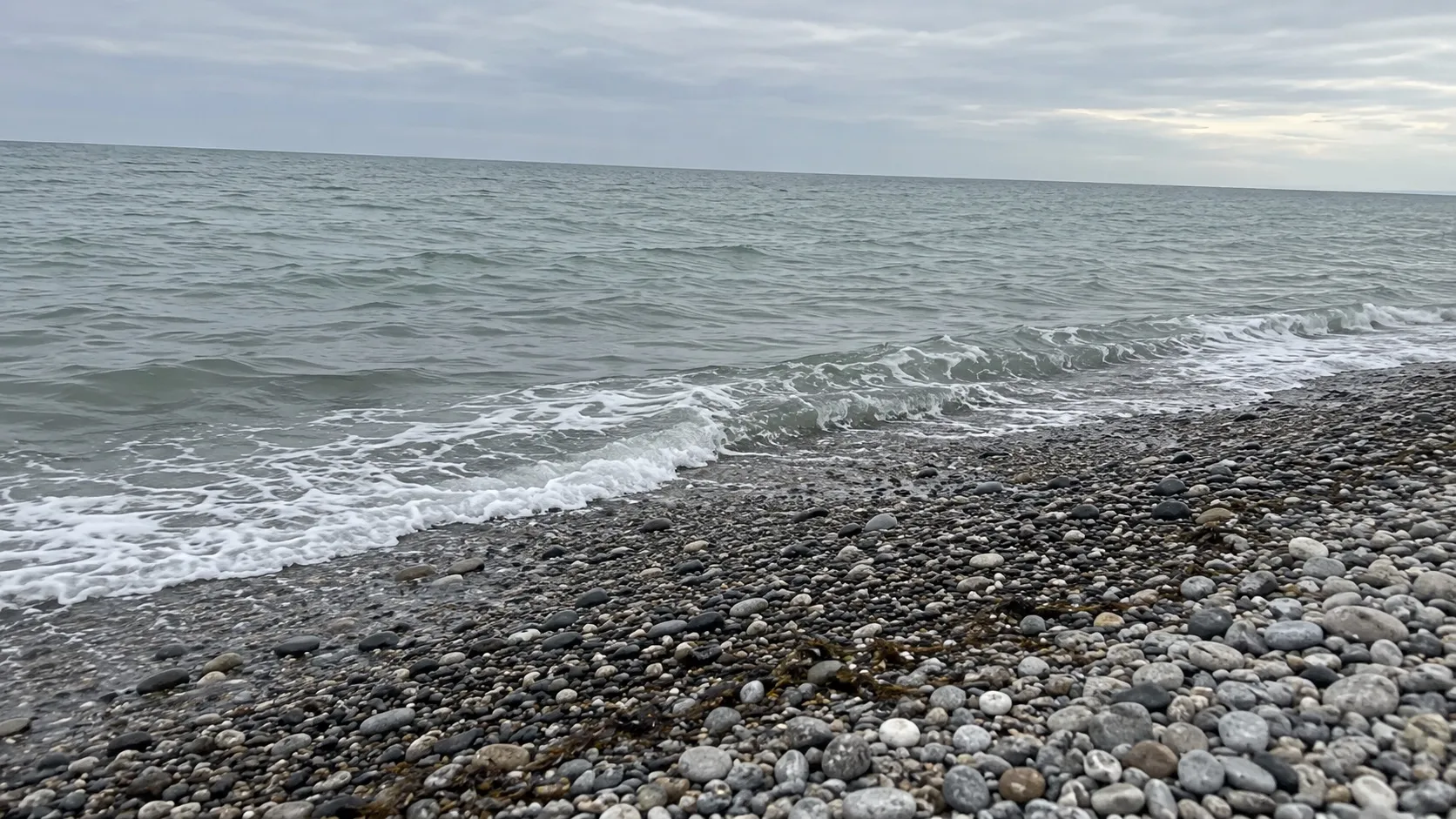 Иллюстрация: ровная галечная полоса у воды, серо-зелёное море