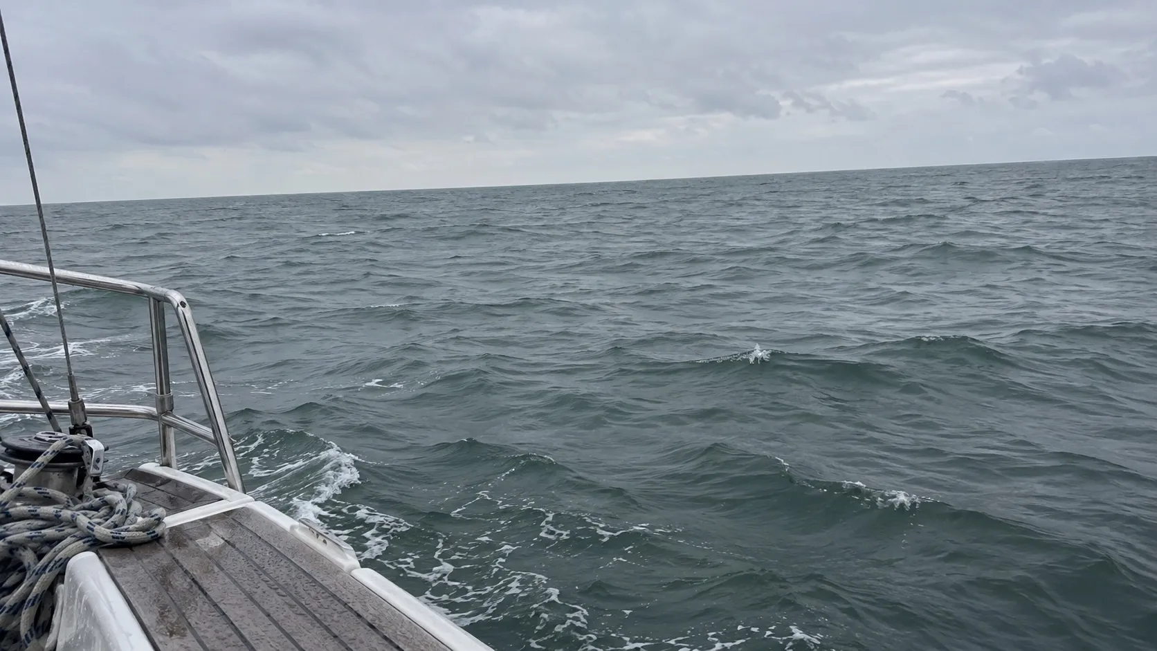 Открытое море с палубы яхты: серо-зелёная вода и пустой горизонт. Иллюстрация, не снимок конкретного рейса