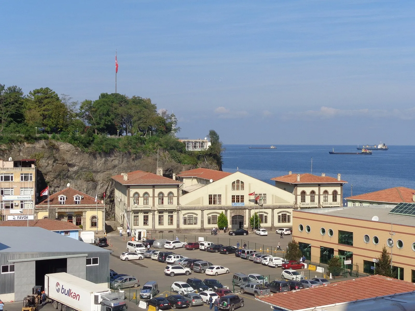 Здание капитана порта в Трабзоне с турецкими флагами, за ним открытое море