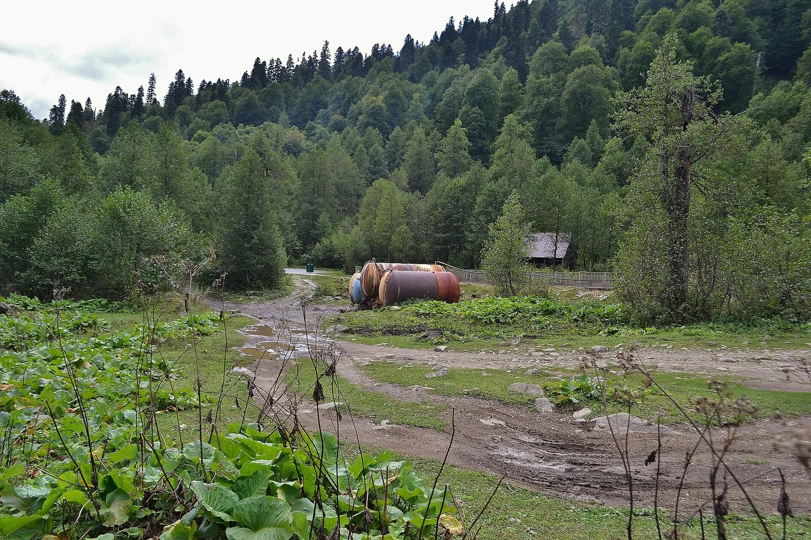 Две ржавые цистерны для минеральной воды на поляне у грунтовой дороги в долине