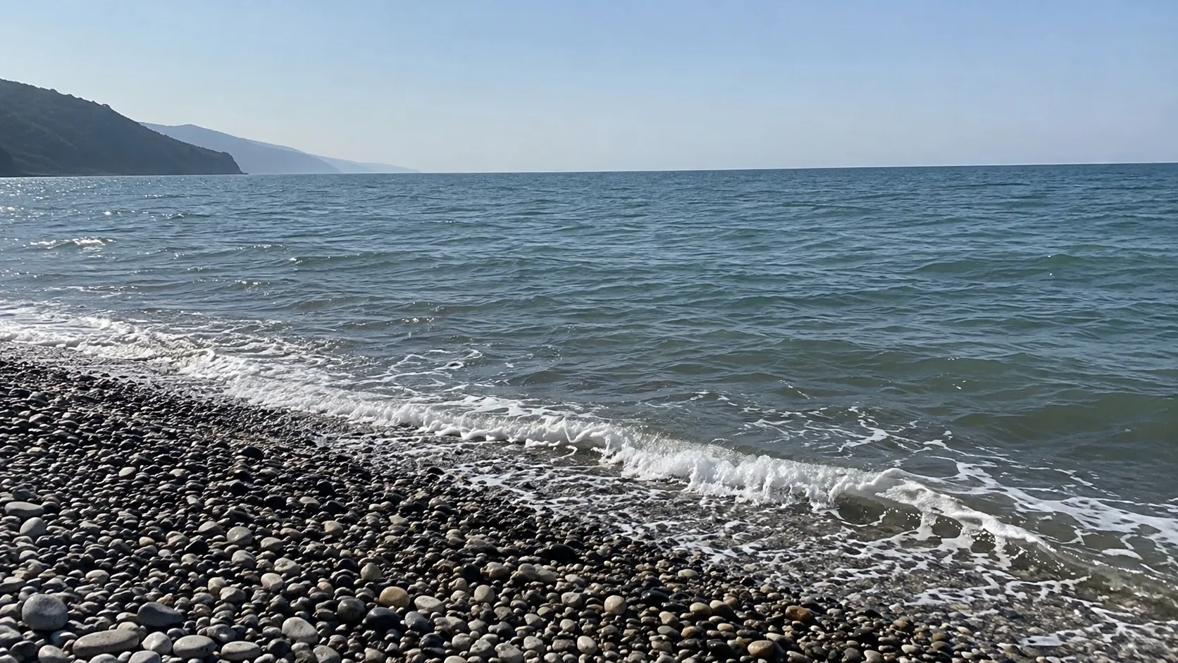 Спокойное серо-зелёное море у галечного берега под ясным небом (иллюстрация)