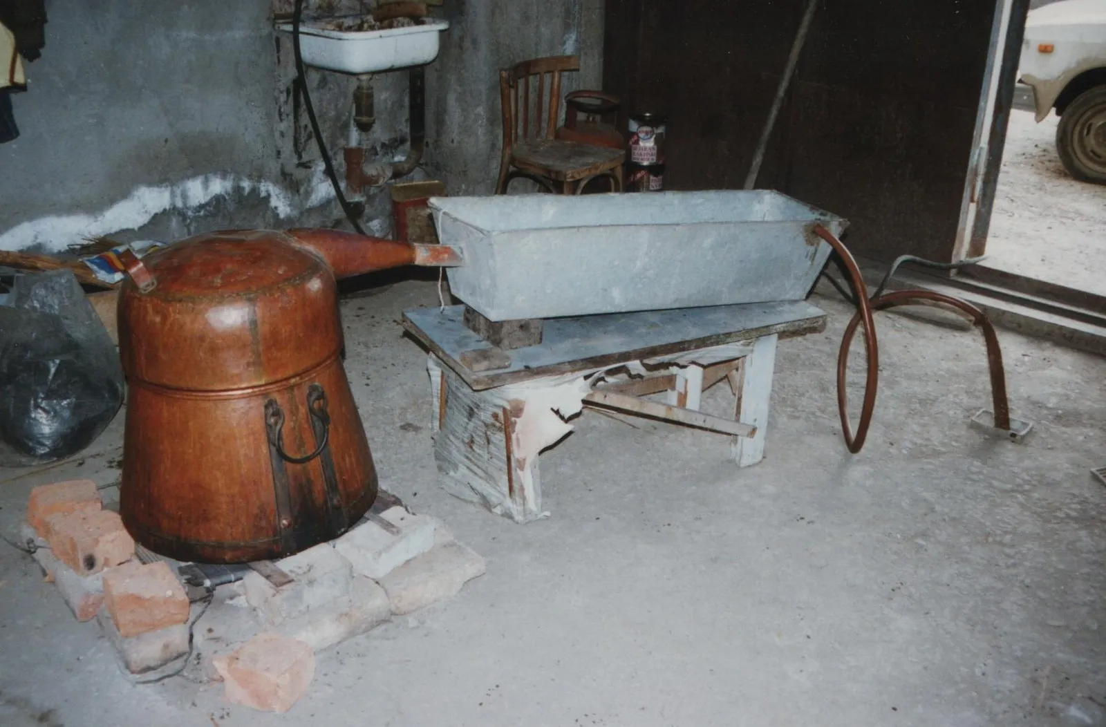 Домашний перегонный куб в Грузии, 1996 год: медный котёл на кирпичах и корыто рядом