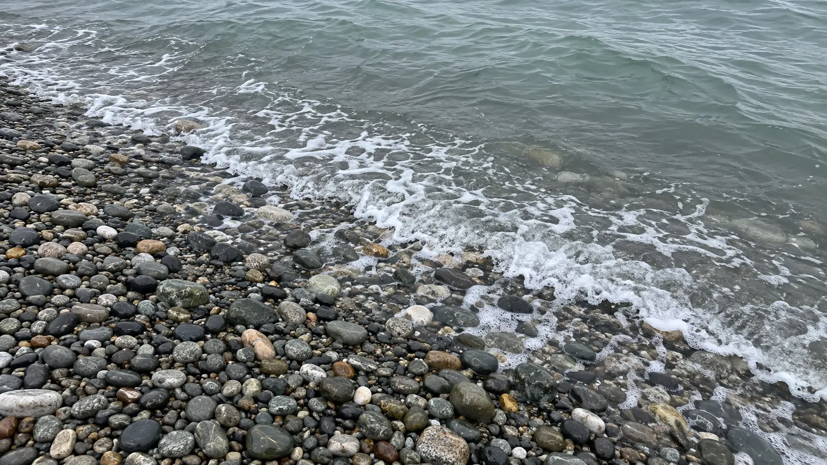 Мокрая галька у кромки серо-зелёной воды, поздняя осень (иллюстрация)