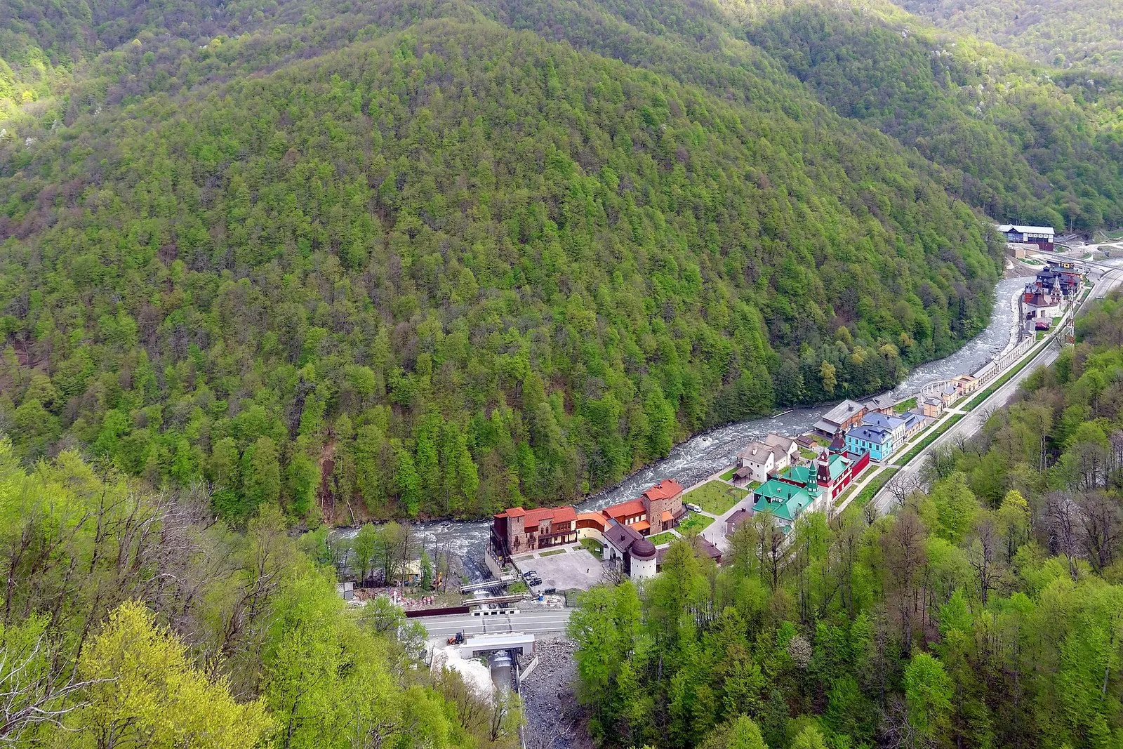 Долина Мзымты в районе курорта «Роза Хутор», вид сверху: застройка у реки среди лесистых склонов, начало мая 2015 года
