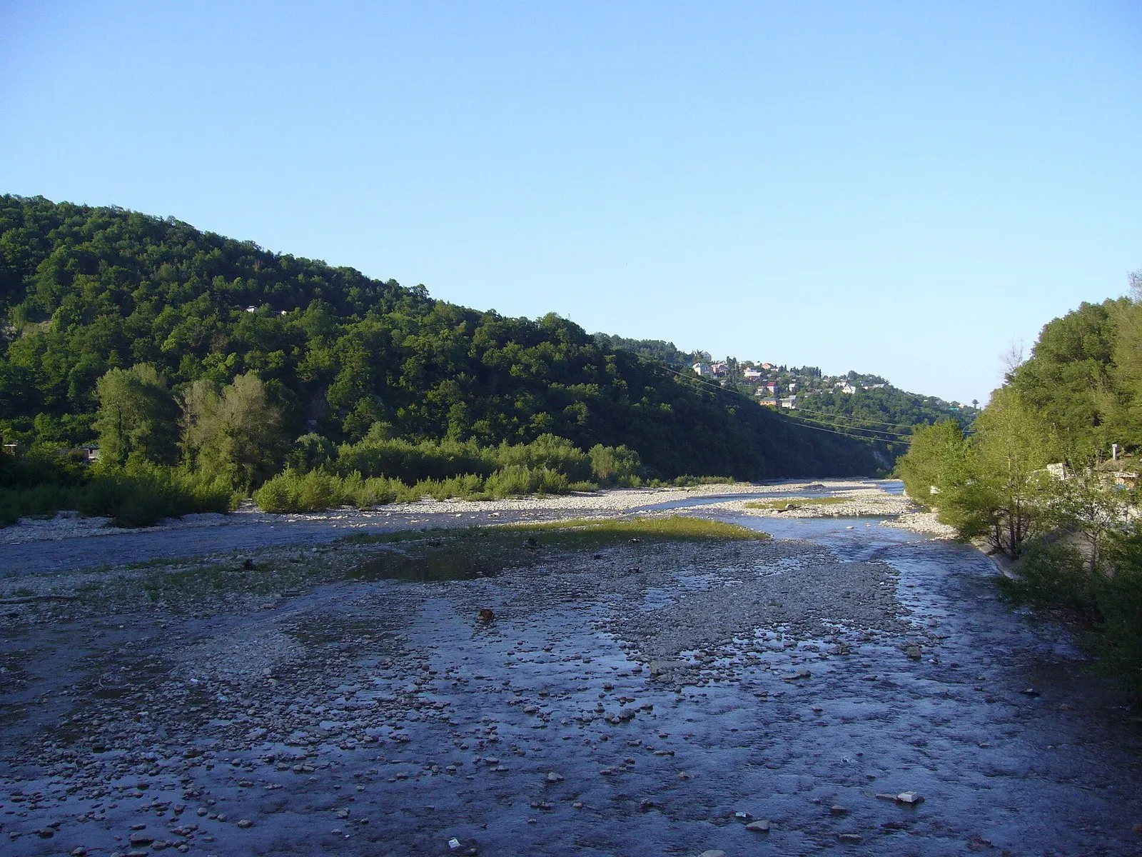 Галечное русло горной реки в малую воду: вода занимает лишь часть ширины