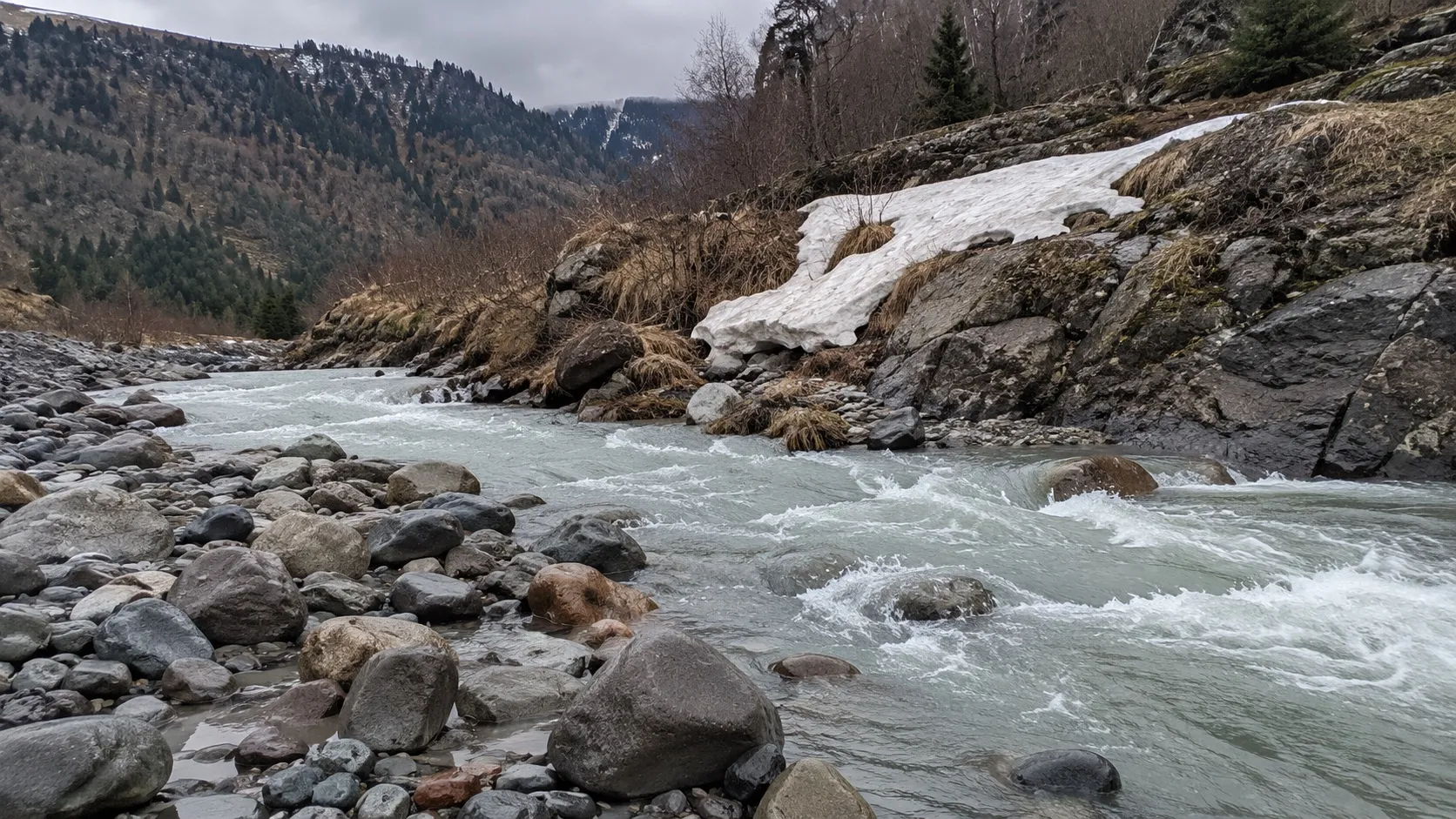 Горный ручей с талой водой: серо-зелёная вода и галька величиной с кулак (сгенерированный кадр)