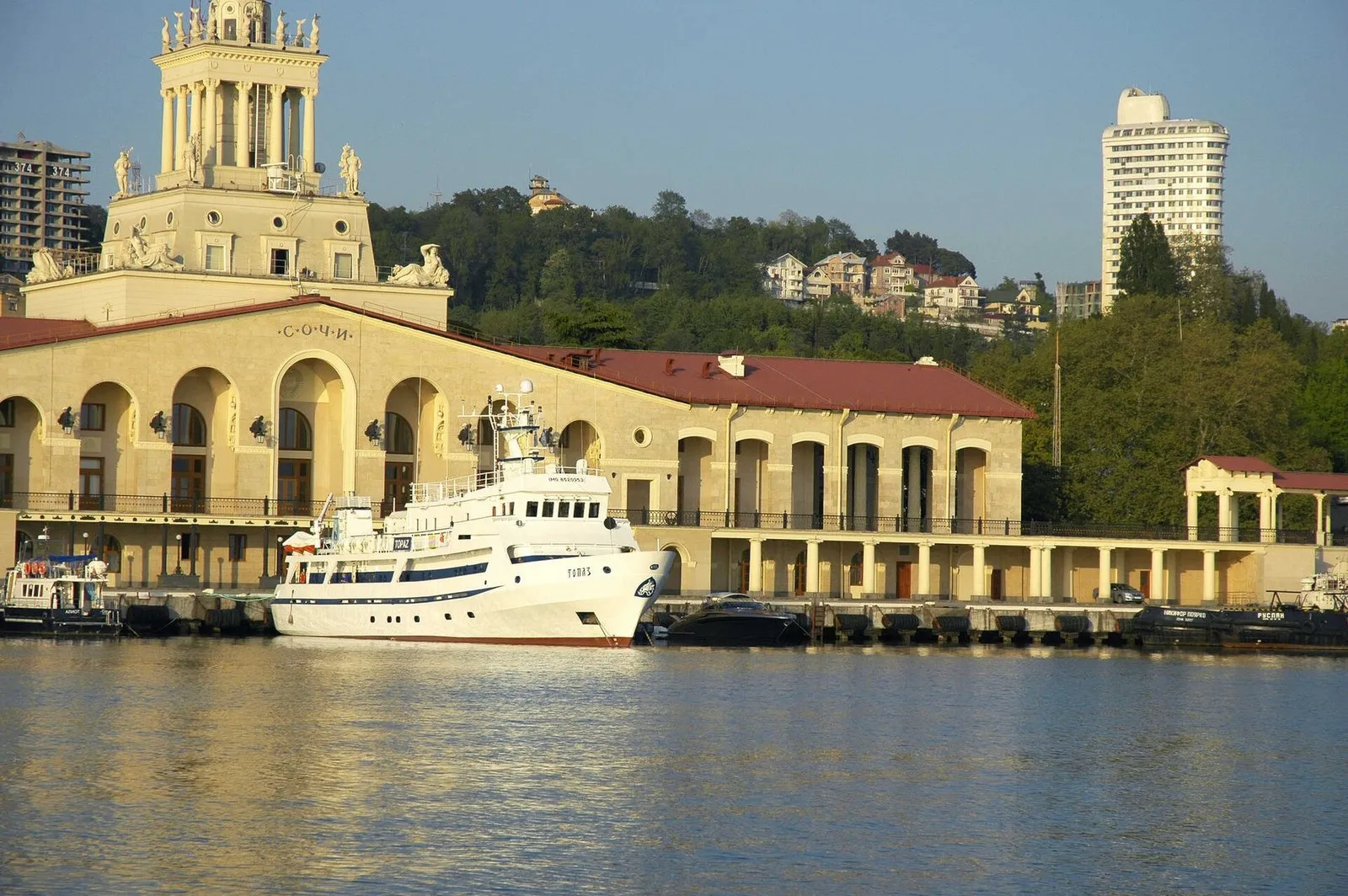 Белое судно у причала Морского порта Сочи, за ним здание Морвокзала
