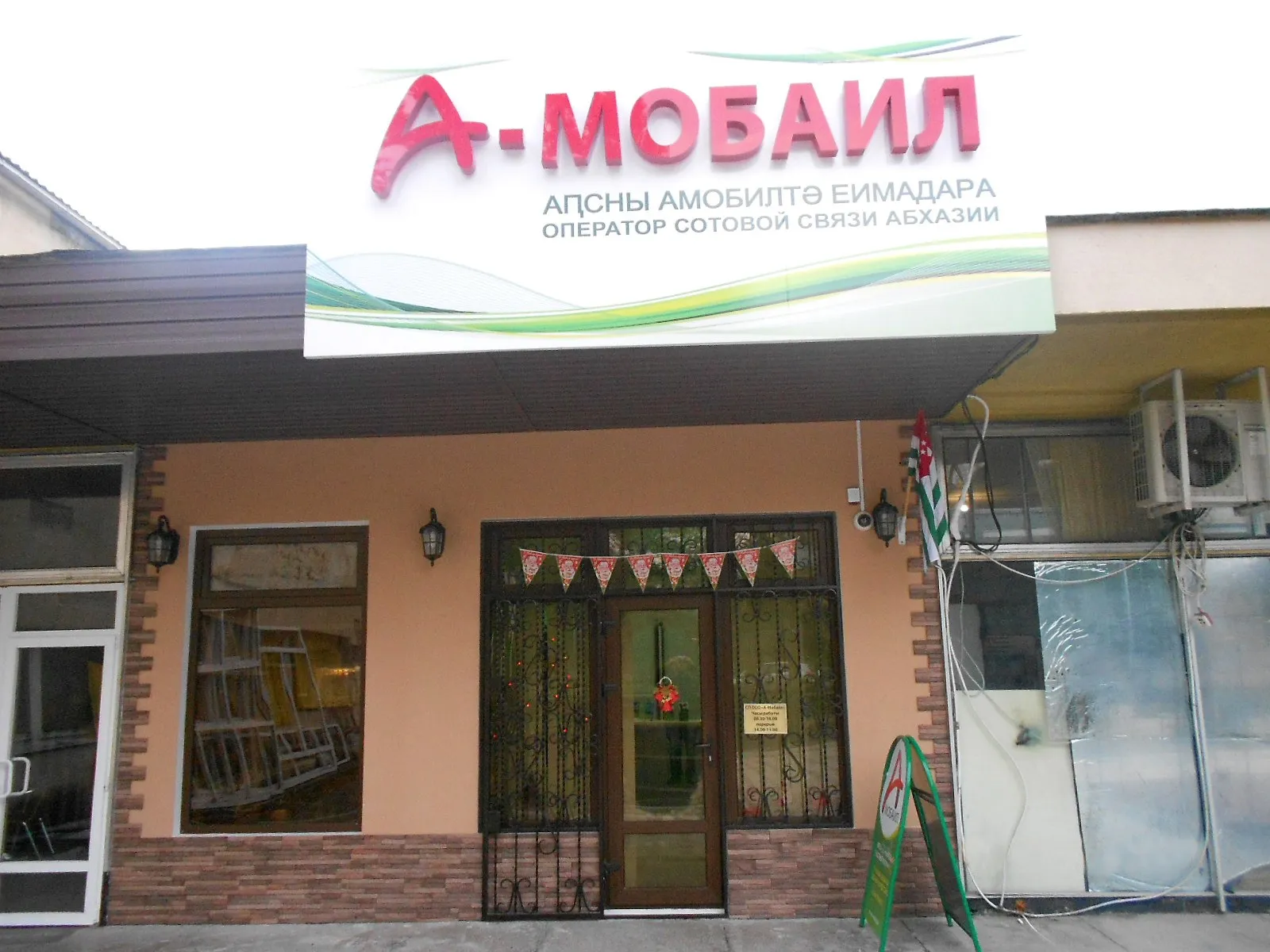 Офис «А-Мобайла», декабрь 2013 года: вывеска «Оператор сотовой связи Абхазии» над входом (фото: Филатов Алексей, Wikimedia Commons, CC BY-SA 3.0)