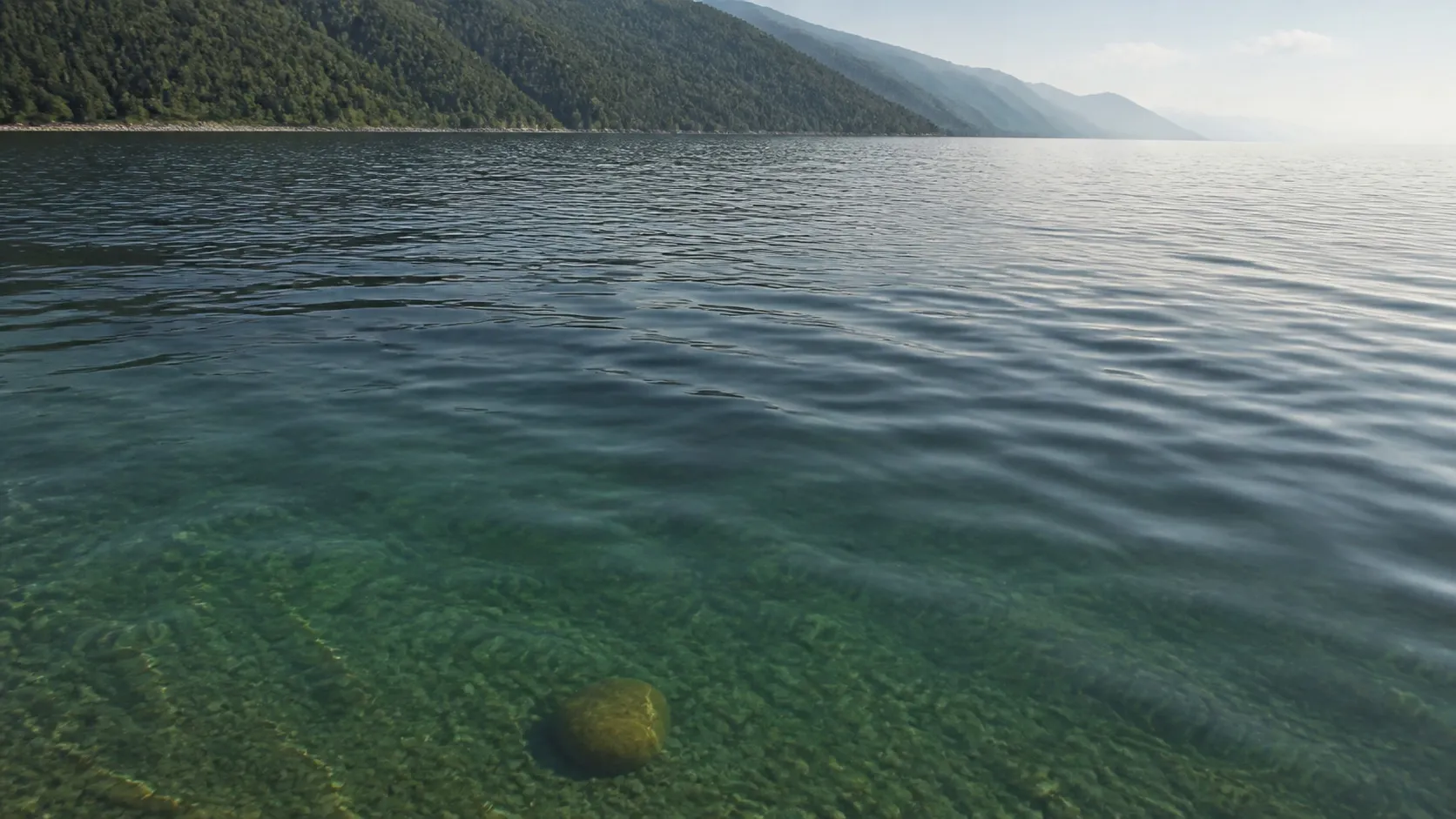 Вблизи вода прозрачная, и видно камни на дне; дальше та же вода превращается в зеркало